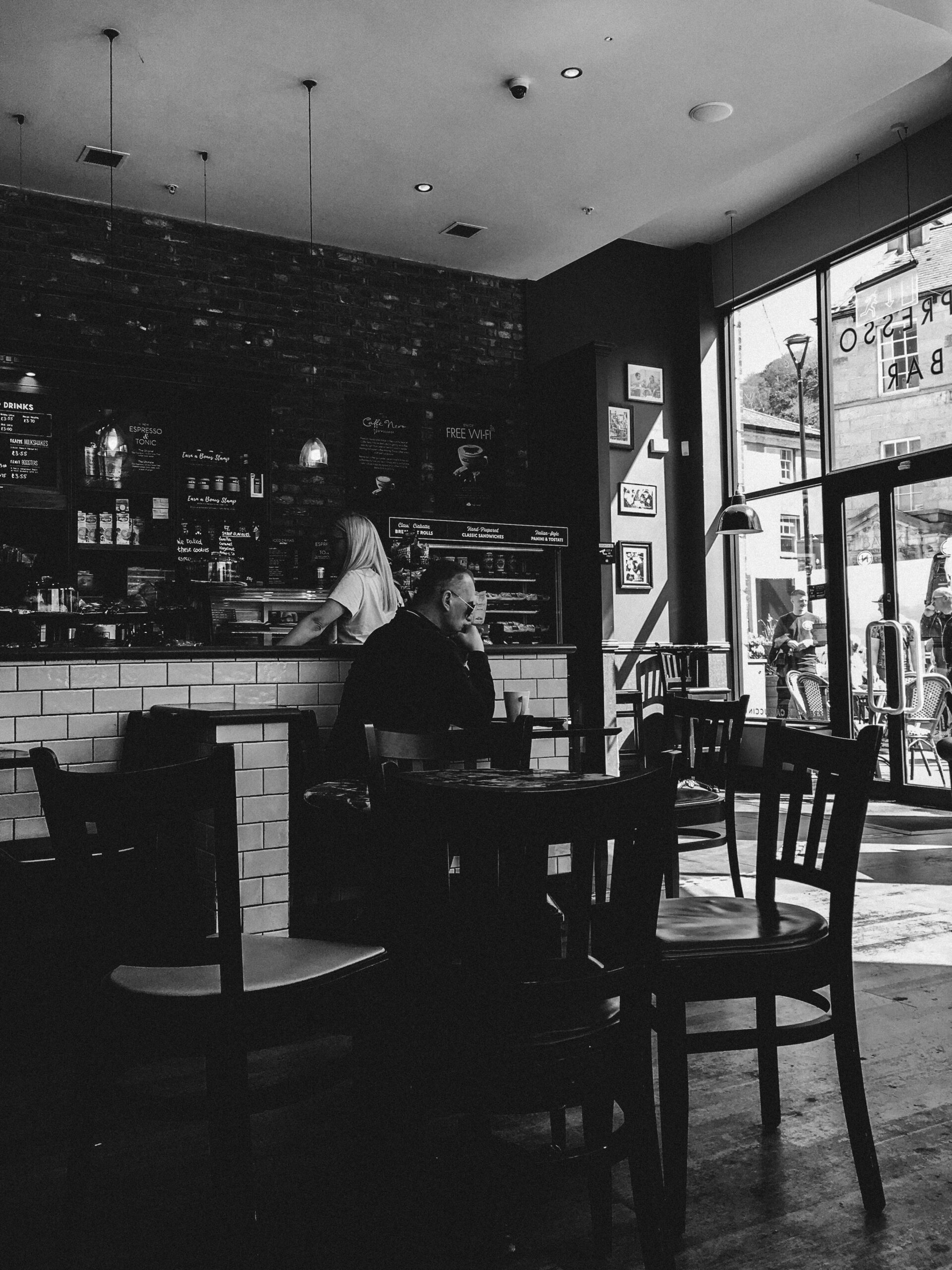 Black and white image of a modern café with people enjoying coffee and conversation.